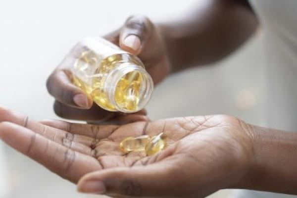 A close-up of a woman pouring capsules into her hand.